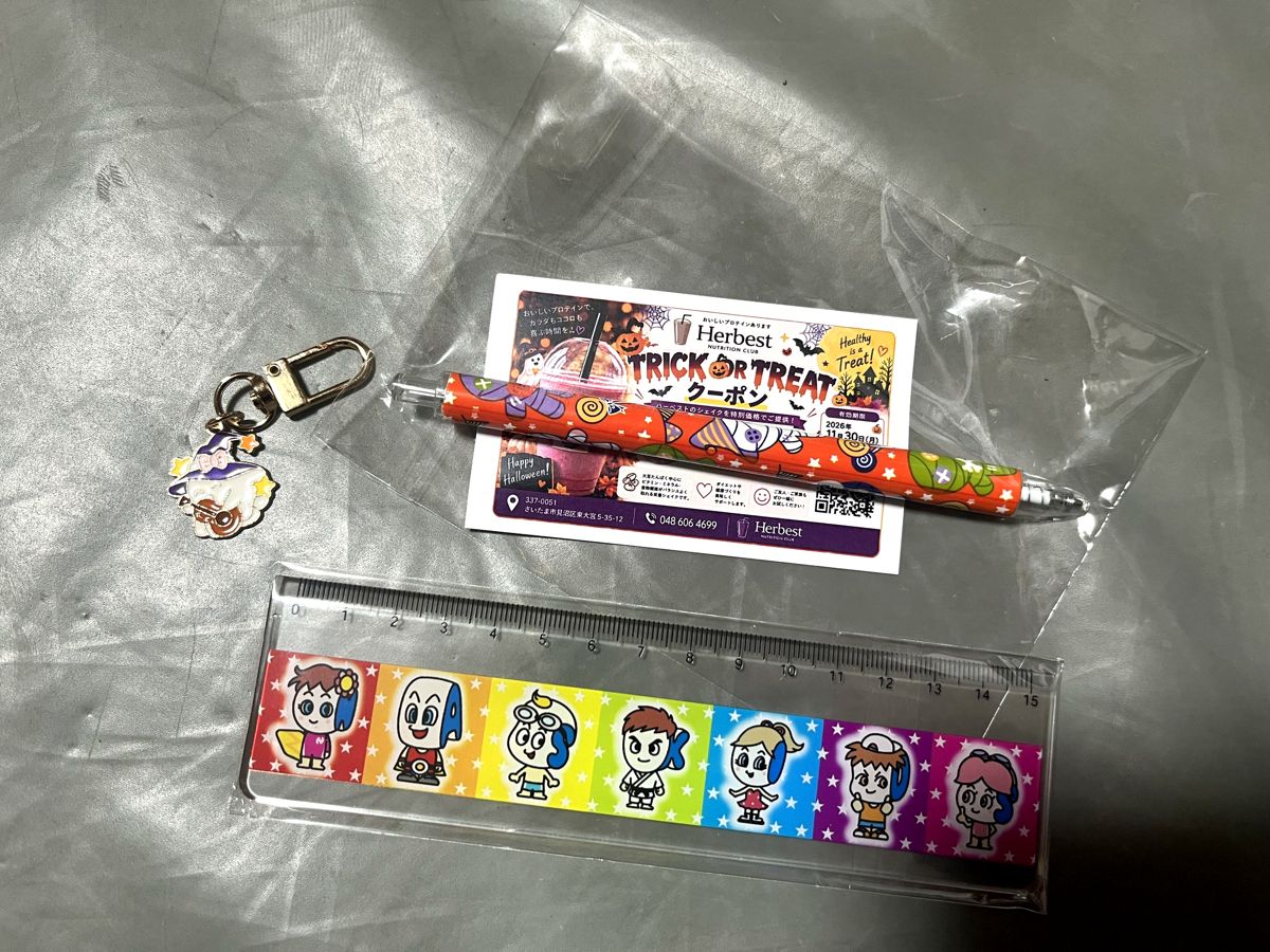 お店を回る途中でいただいたグッズ。ハーベストのハロウィンクーポン、オレンジ色のペン、魔女のキーホルダー、定規