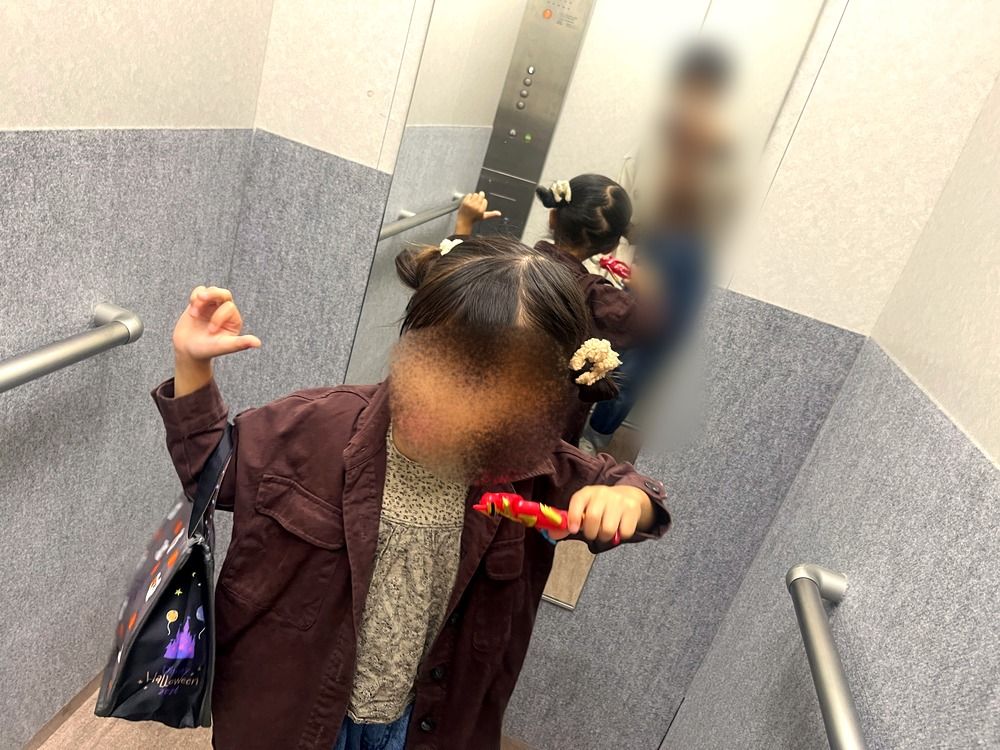 会場へ向かうエレベーターでポーズをとる5歳の子ども(顔はぼかし)