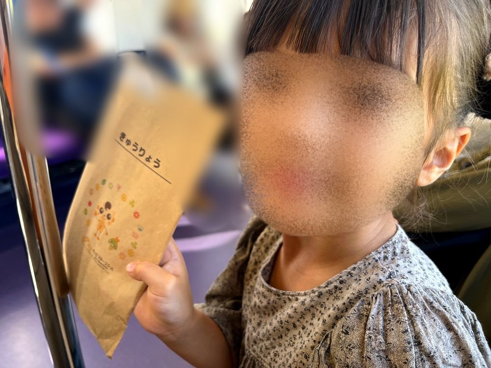 帰りの電車で、もらったお給料袋を見せる5歳の子ども(顔はぼかし)