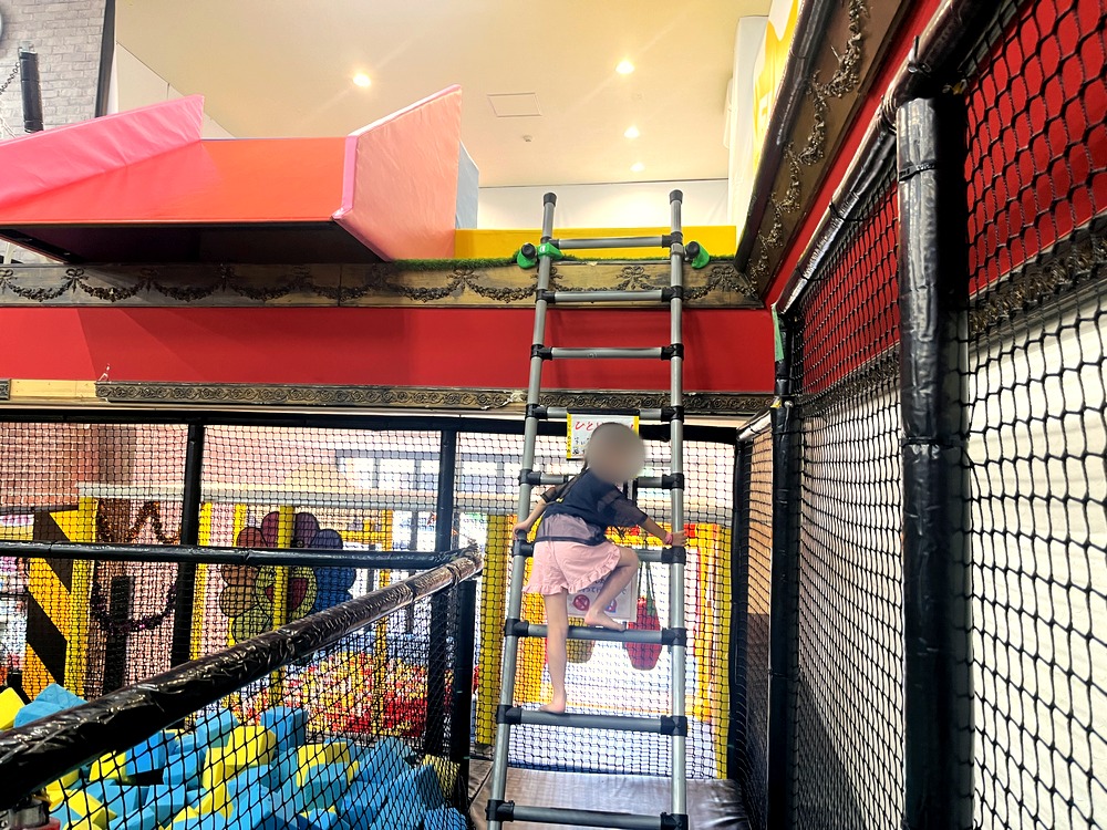 スポンジのプールの上のはしごを登る子ども