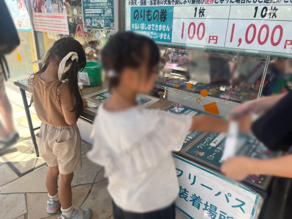 乗り物券売り場の前で、フリーパスに年齢を書いて身につける子どもたち