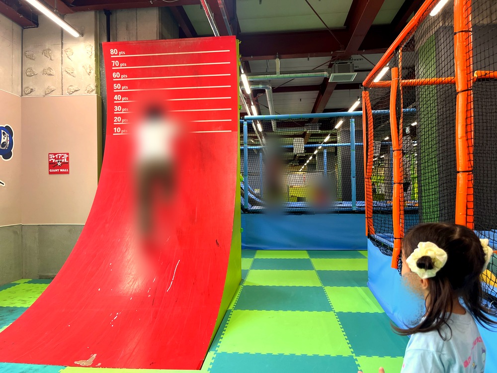 大人が赤い反り立つ壁を駆け上がる様子と、それを見る5歳の子ども