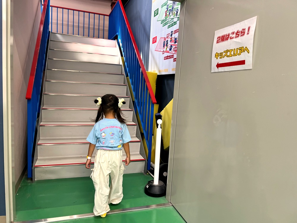 ジュニアアスレチックのある2階へ階段を上る5歳の子ども